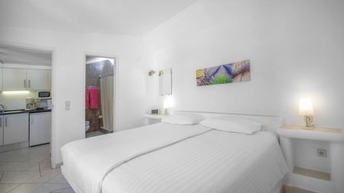 - une chambre blanche avec un lit blanc et une cuisine dans l'établissement Quinta Paraiso da Mia - 1 Bedroom Apartment, à Luz