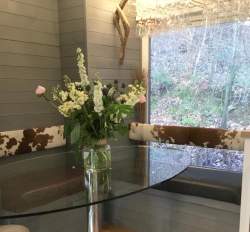 a glass table with a vase of flowers on it at Mistletoe One Luxury Lodge with Hot Tub Windermere in Windermere