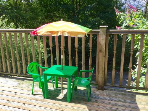 a table and two chairs and an umbrella on a deck at Mistletoe One Luxury Lodge with Hot Tub Windermere in Windermere