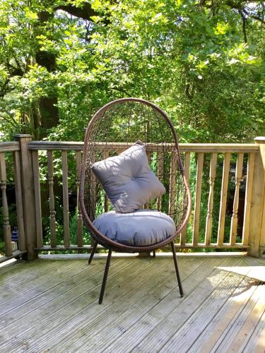 a wicker chair with a pillow sitting on a deck at Mistletoe One Luxury Lodge with Hot Tub Windermere in Windermere