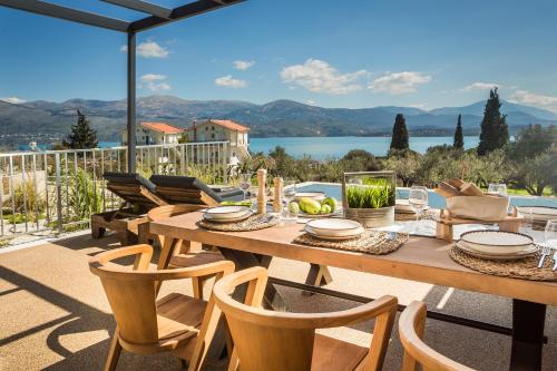 een houten tafel en stoelen op een patio met uitzicht bij Ionian Village in Lixouri
