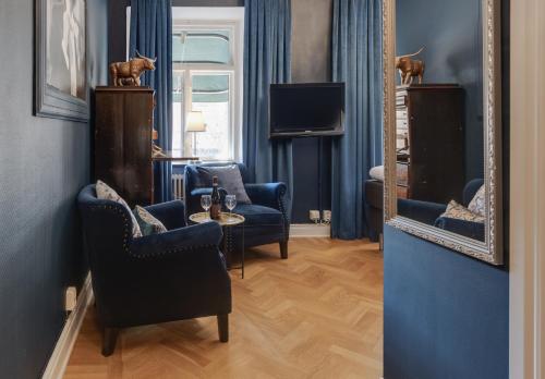 a living room with blue chairs and a mirror at Cameo Boutique Hotell in Ystad