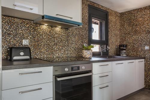 a kitchen with white cabinets and a sink at Ionian Village in Lixouri