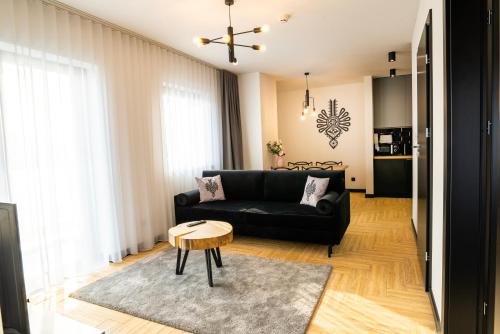 a living room with a black couch and a table at Stylchyn 90 Apartamenty nad Jeziorem Czorsztyńskim in Kluszkowce