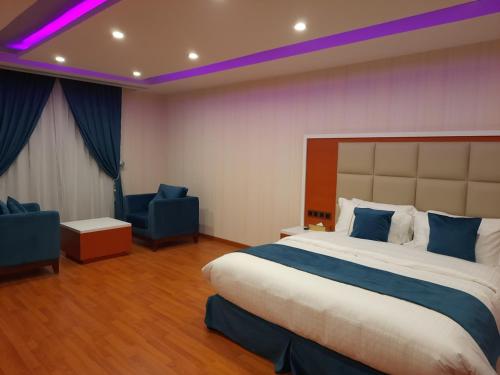 a hotel room with a large bed and two chairs at Villa Park in Al Khobar
