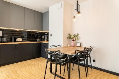 a kitchen with a wooden table and black chairs at Stylchyn 90 Apartamenty nad Jeziorem Czorsztyńskim in Kluszkowce