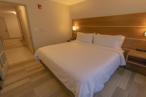 a bedroom with a large white bed with a wooden headboard at Holiday Inn Express & Suites Manassas by IHG in Manassas
