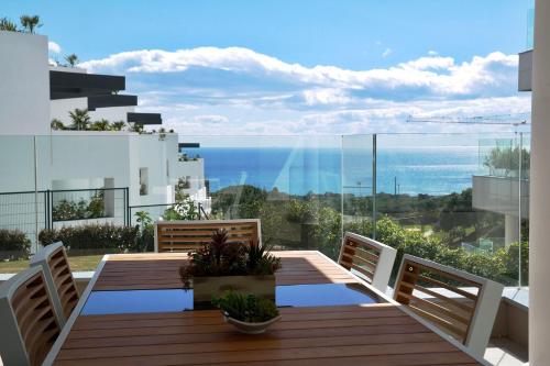 a balcony with a wooden table and chairs and the ocean at LUXURIOUS VACATIONAL HOME WITH 3 BEDROOMS AND POOL AT CABOPINO GOLF MARBELLA by Solrentspain in Marbella