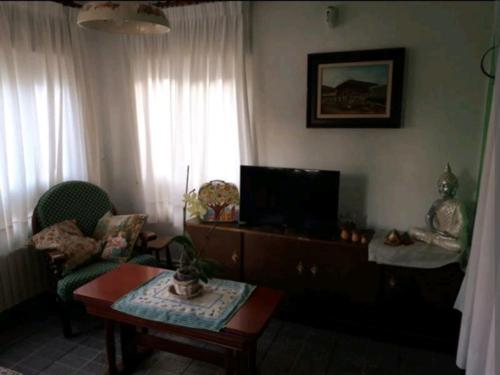 uma sala de estar com uma televisão, um sofá e uma mesa em Casa Cascabelia. Cerca de Santillana del Mar em Valles