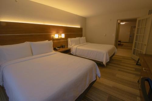 a hotel room with two beds with white sheets at Holiday Inn Express & Suites Manassas by IHG in Manassas
