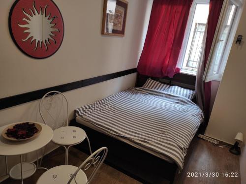 una piccola camera con un letto e due tavoli e una finestra di Retro Mini Apartment a Zemun