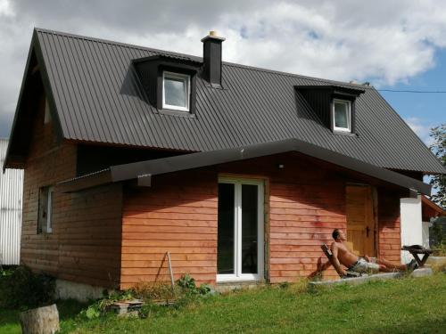 a man sitting on the porch of a house at Mountain village in Žabljak