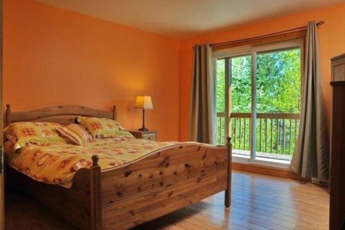 sypialnia z łóżkiem i dużym oknem w obiekcie Le Très-Chic - SPA, billard, souvenirs w mieście Baie-Saint-Paul