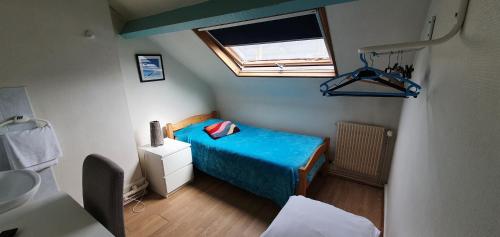 a small bedroom with a blue bed and a window at Hôtel de la poste in Saint-Valery-en-Caux
