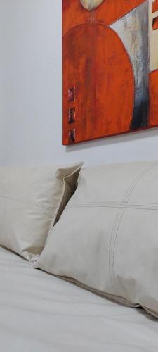 a bed with white pillows and a painting on the wall at Departamento Plaza Colón, súper equipado a una cuadra del mar in Mar del Plata