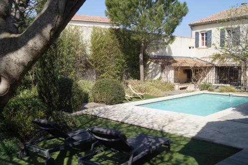 a backyard with a swimming pool and two lawn chairs at Domaine de la Girafe in Eyragues