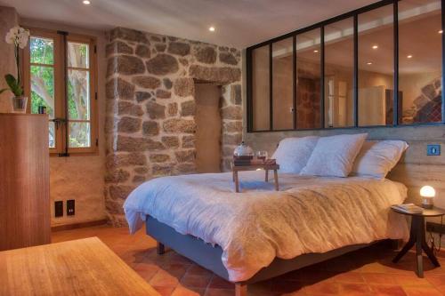 a bedroom with a large bed with a stone wall at Appartement de charme à Olmeto in Olmeto