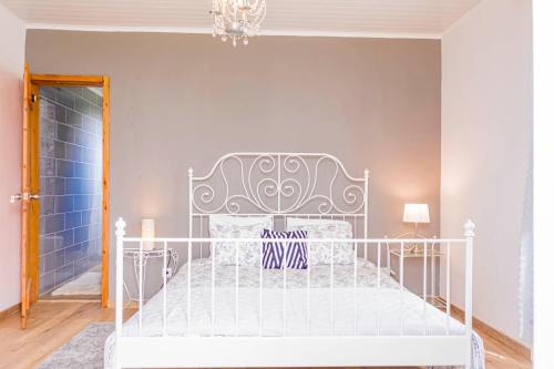 a white bed in a room with a blue wall at Candelária House in Candelária