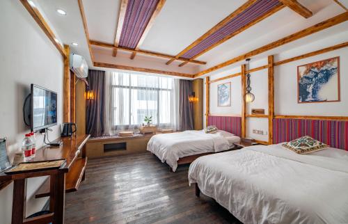 a hotel room with two beds and a television at Zhangjiajie Highlights Guesthouse in Zhangjiajie