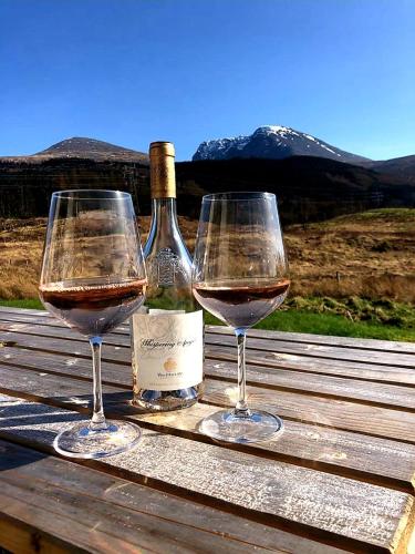 two glasses of wine sitting on a wooden table at Tower Ridge House in Fort William