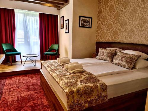 a bedroom with a large bed and two green chairs at Carpe Diem Boutique Hotel in Zenica