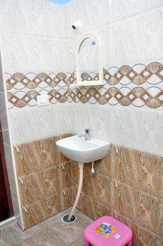 a bathroom with a sink and a pink stool at Maanas Homestay in Tirupati