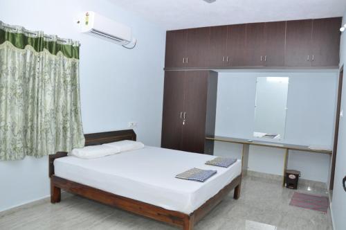 a bedroom with a bed and a desk in it at Maanas Homestay in Tirupati