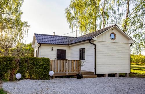 una piccola casa bianca con una panchina davanti di Björkeslund a Veberöd