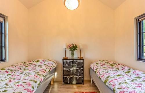 een slaapkamer met 2 bedden en een tafel met bloemen bij Björkeslund in Veberöd
