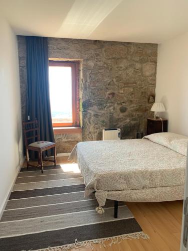 a bedroom with a bed and a stone wall at Bela Vista in Penhas da Saúde
