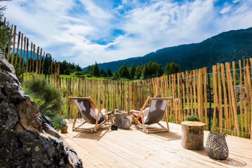 two people sitting in chairs on a deck with a fence at Mountain Hostel Tarter in El Tarter