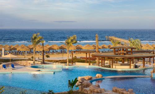 ein Resort mit 2 Pools und Sonnenschirmen und dem Meer in der Unterkunft Lazuli Hotel, Marsa Alam in Al-Qusair