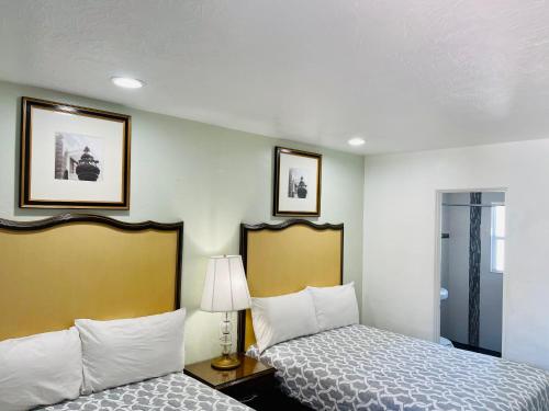 a hotel room with two beds and a lamp at Siesta Inn Sarasota - Indian Beach in Sarasota