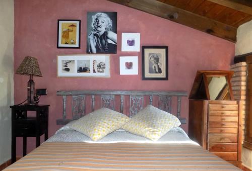 1 dormitorio con 1 cama con cuadros en la pared en Casas Rurales Lagunas de Ruidera - Piscina, en Ossa de Montiel