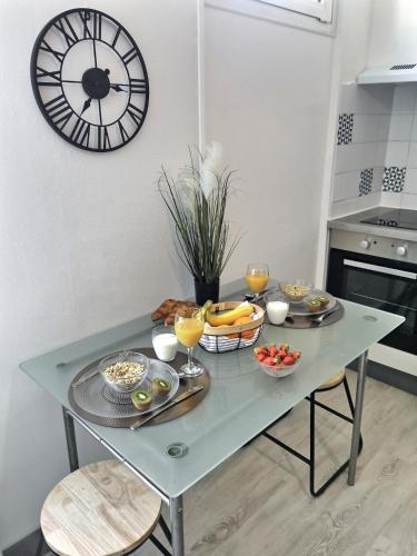 une table avec des bols de fruits et une horloge sur le mur dans l'établissement Studio ZEN Tout Confort Proche Hyper-Centre, à Cognac