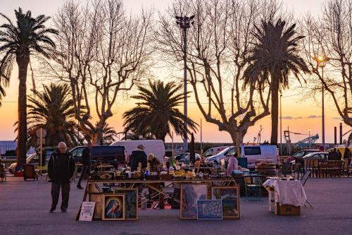 a group of people at an outdoor market with palm trees at Sud Hôtel Restaurant in Bastia