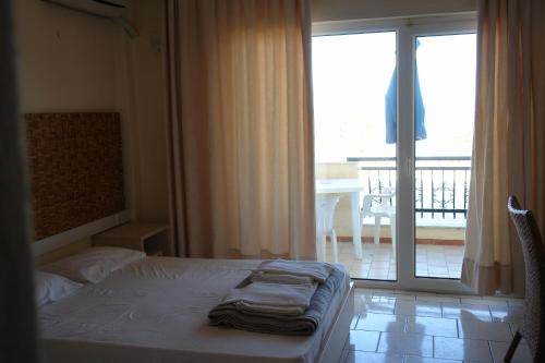 a bedroom with a bed and a large window with a balcony at Pantheon Beach Hotel in Olympic Beach