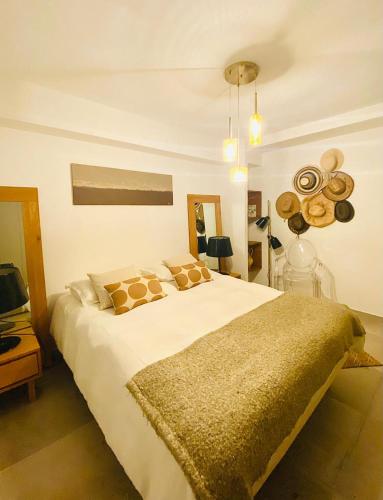 une chambre avec un grand lit blanc avec des oreillers dans l'établissement Le Jardin Caché, à Sanary-sur-Mer