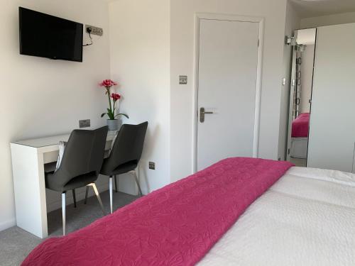 a bedroom with a bed and a desk with two chairs at The Bungalows Guesthouse in Threlkeld