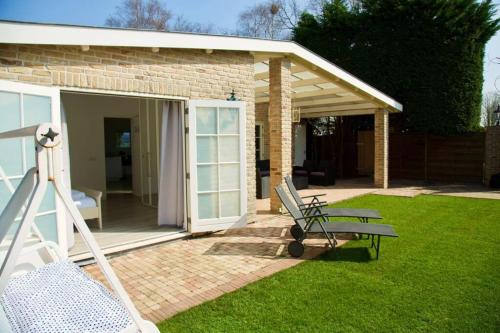 une maison avec une terrasse couverte et un banc dans une cour dans l'établissement Spaanse Bungalow nabij Amsterdam with Sauna and steam sauna, à Vijfhuizen