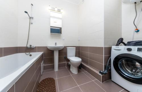 a bathroom with a toilet a sink and a washing machine at Стильна та затишна квартира у новому будинку на Оболоні, 5 поверх in Kyiv