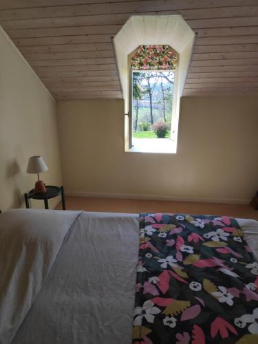 - une chambre avec un lit doté d'une couverture fleurie et d'une fenêtre dans l'établissement Au Château Juillac, à Juillac