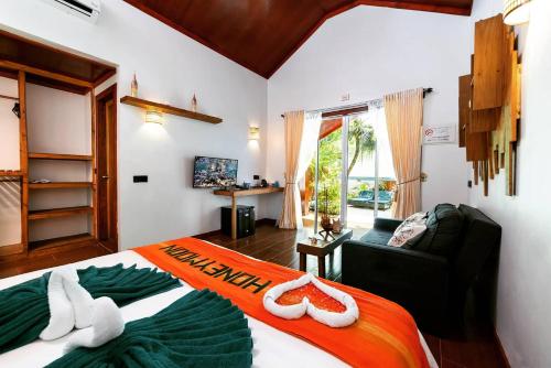 a bedroom with a bed and a couch and a window at Beach Villa Ukulhas in Ukulhas