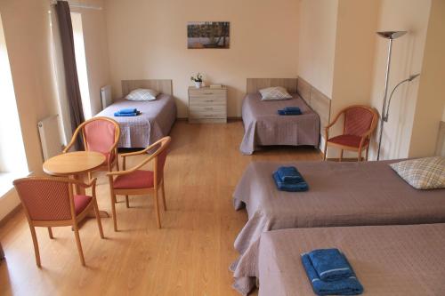 Cette chambre comprend deux lits, une table et des chaises. dans l'établissement Parko Studija, à Birštonas