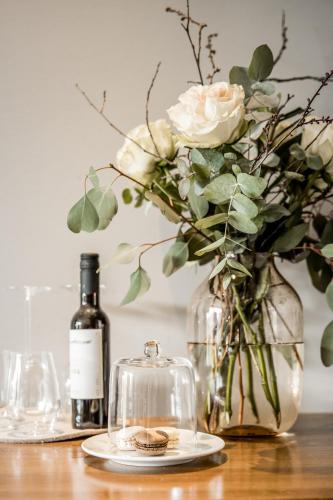 a table with a vase with flowers and a bottle of wine at Hotel Restaurant Spa Torkel in Nonnenhorn