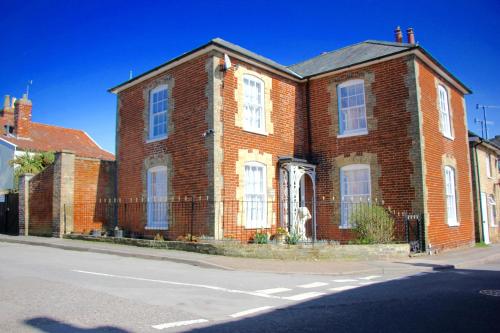 an old brick house with a dog in front of it at Sleeps14 Seaside Luxury House on the Suffolk Coast in Saxmundham