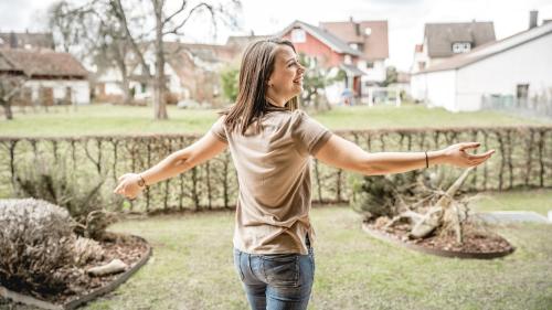 a woman standing in a yard with her arms outstretched at Hotel Restaurant Spa Torkel in Nonnenhorn