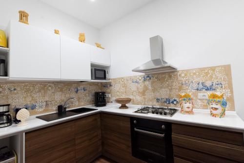 a kitchen with white cabinets and a stove top oven at Fervore Luxury Rooms in Palermo