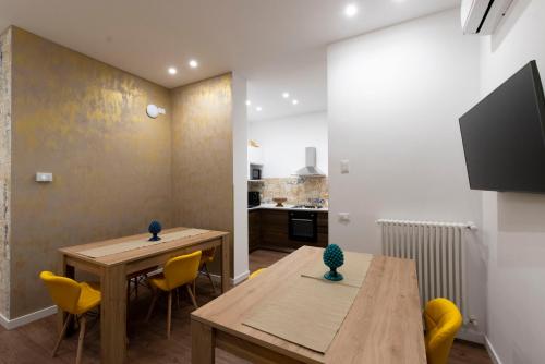 a kitchen and dining room with two tables and yellow chairs at Fervore Luxury Rooms in Palermo
