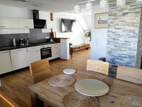 una cocina con mesa de madera y una cocina con armarios blancos. en Ferienwohnung Maja en Waldkirch